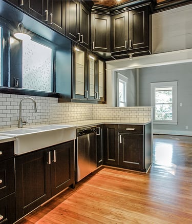 Modern kitchen with black shaker cabinets, white subway tile backsplash, and farmhouse sink.