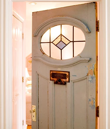 Vintage light blue interior door with an oval stained glass window and brass U.S. Mail slot.