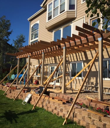 Angled view of a large residential wood deck project mid-construction with temporary support bracing.