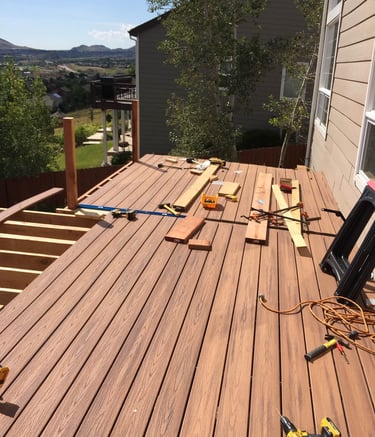 Progress shot of laying down durable composite deck boards on new joists during a backyard build.