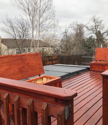 Finished outdoor living space in Golden with a Brewer Construction wooden deck, built-in benches, and hot tub.