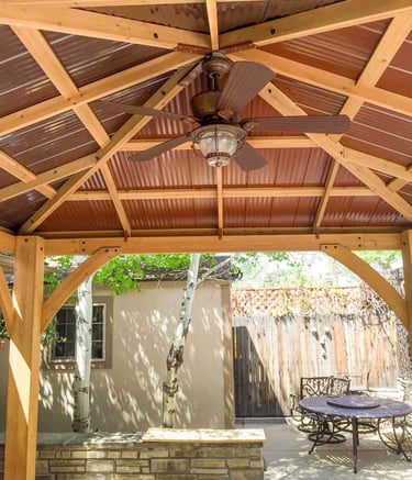 Finished wood framing and a ceiling fan inside a custom backyard pergola in littleton