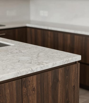 A close-up, high-angle shot of a custom-built kitchen island corner. The craftsmanship shows seamless joins in high-end quartz countertops and dark wood cabinetry (#4A433A). The lighting is soft and professional, highlighting a sophisticated and trustworthy mood with neutral tones of #F7F4EF in the background.