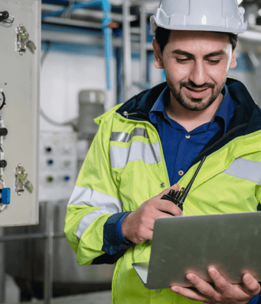 Industrial technician reviewing data and listening to instructions via PoC radio