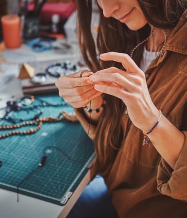  Un joyero en una mesa de manualidades ensamblando un collar de cuentas hecho a mano