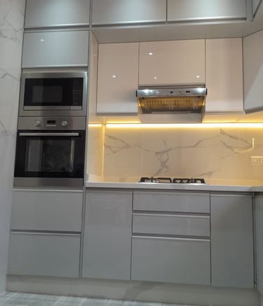 Modern gray and white gloss kitchen cabinets with marble backsplash and LED under-cabinet lighting.