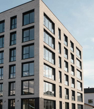 Wide shot of a newly constructed modern apartment building with large glass windows and clean brickwork, set against a crisp Northern European sky, high-end real estate photography.