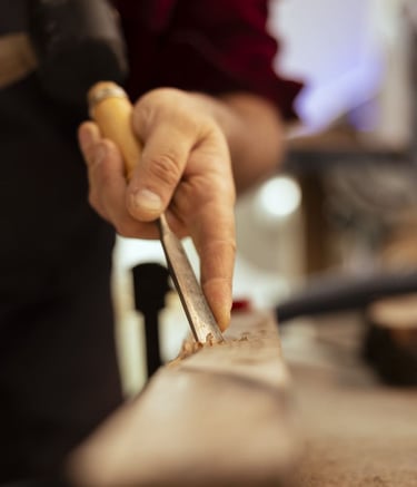 Artesano experto en carpintería utilizando un cincel metálico afilado para tallar detalles en madera