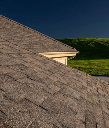 A high-end architectural photograph of a modern residential roof in the USA during golden hour. The shingles are crisp and perfectly aligned. In the background, a lush emerald green lawn and deep navy blue sky provide a premium, trustworthy atmosphere. Sharp focus, clean composition.