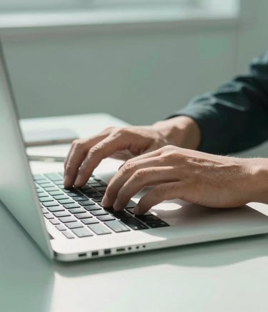 Close-up of professional hands typing on a high-end laptop keyboard in a sunlit Italian studio. The atmosphere is professional and modern, with soft mint and muted teal color tones throughout the minimalist workplace.