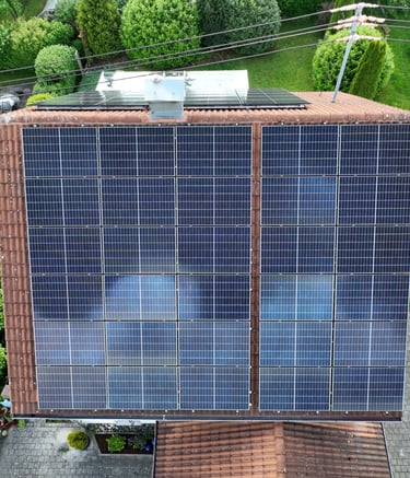 Aerial view of a residential rooftop with solar panels installed on orange tiles for renewable energy.