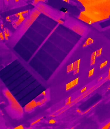 Thermal imaging of a residential house showing heat loss through windows and solar panel efficiency.