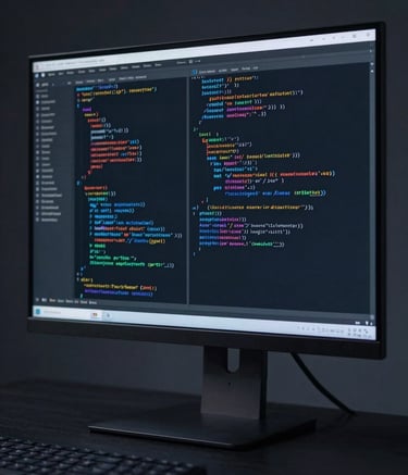 An abstract, sharp photograph of a high-resolution workstation monitor showing lines of code. The surrounding environment is a clean, dark-themed North American / US studio. The palette is dominated by deep navy and steel blue-grey tones.