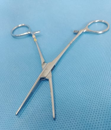 Pinça Kelly reta sobre tecido azul estéril, usada para pinçar vasos e tecidos.