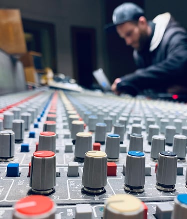 Mixing console close-up with producer working in blurred background