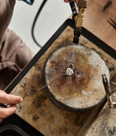  Joyero que utiliza un soplete de gas para soldar un anillo de plata en un bloque de soldadura