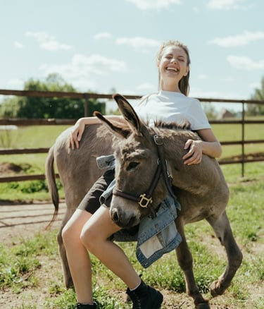 a woman in a white shirt is holding a donkey