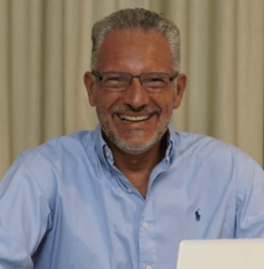 a man in a blue shirt and glasses sitting at a table