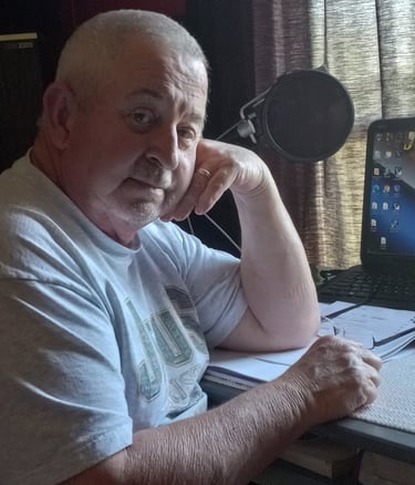a man sitting at a desk with a laptop and a microphone