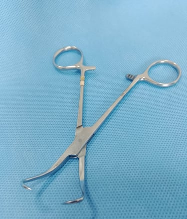 Pinça Backhaus cirúrgica sobre tecido azul estéril, utilizada para fixar campos cirúrgicos.