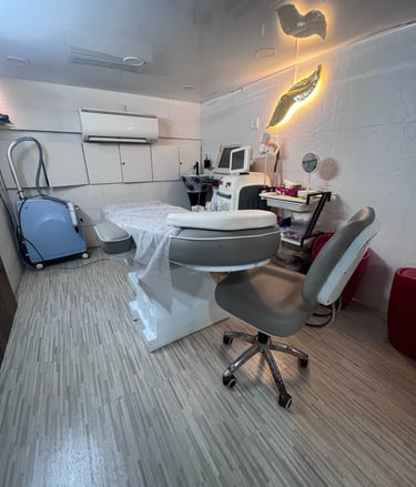 Dr Seema Sheen Aesthetics treatment room with a bed, desk, and chair