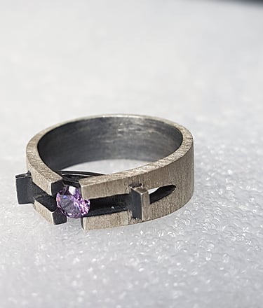 a ring with a purple stone ring on top of a white surface
