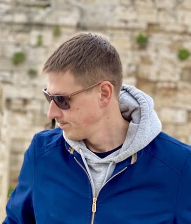 a man in a blue jacket and sunglasses posing in Medieval town in Rhodes Greece