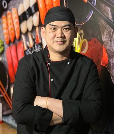 a chef in a black uniform and a black hat