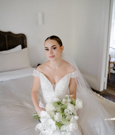 a bride in a white wedding dress sitting on a bed