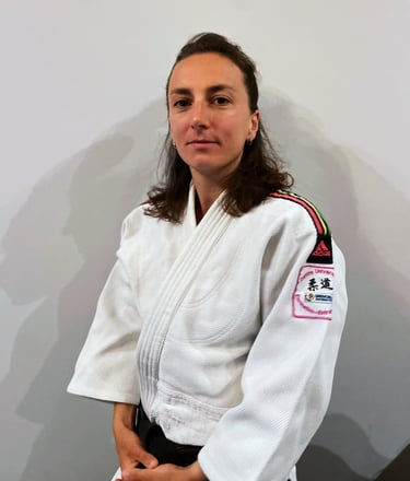 Une femme en kimono de Judo, portant une ceinture noire.