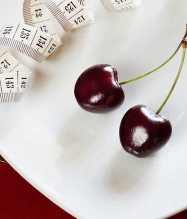 a fork and two cherries with a measuring tape on a plate