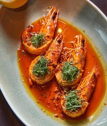 Spicy grilled prawns with fresh herbs and citrus, served in a rich sauce at The Emory Hotel.