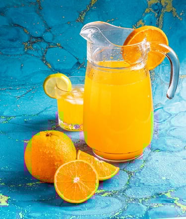 a pitcher of orange juice with oranges and lemon