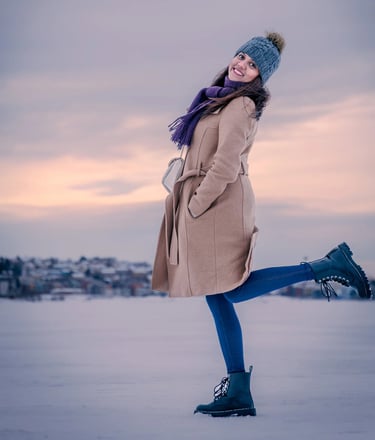 a woman in a coat and hat standing in the snow