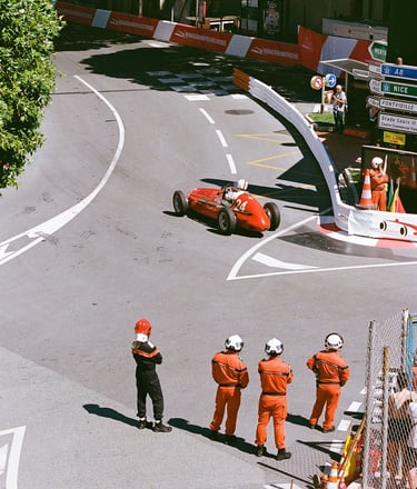 a group of race marshals watching a red race car go through a corner