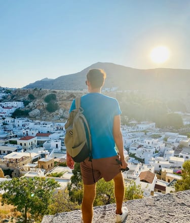 a man standing on a rock ledge overlooking a city