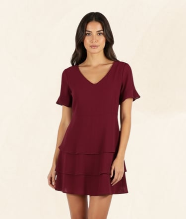 Woman wearing a burgundy short sleeve tiered mini dress with a v-neckline.