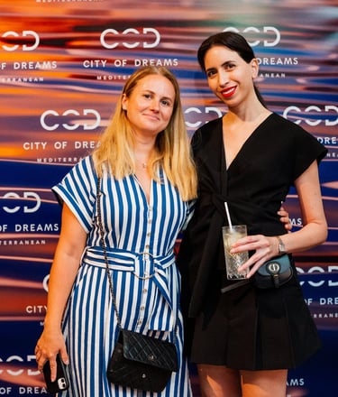 two women standing next to each other in front of a city backdrop