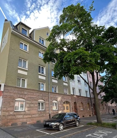 Mehrfamilienhaus mit grün-beiger Fassade und Sandstein im Erdgeschoss in Fürth-Ronhof.