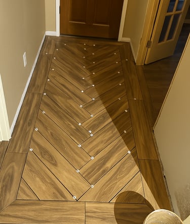 alt="Flooring installation in progress with herringbone tiles"