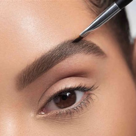 a woman with a eyebrow brush and eyebrow makeup