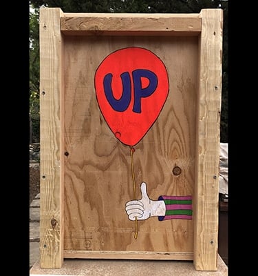 Shipping crate for Talbotics sculpture with image of hand holding a balloon drawn on it.