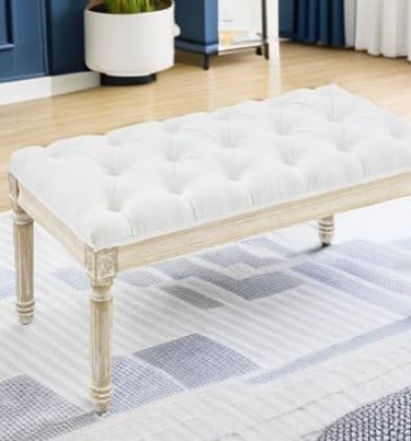 White tufted upholstered bench with carved light wood legs on a modern