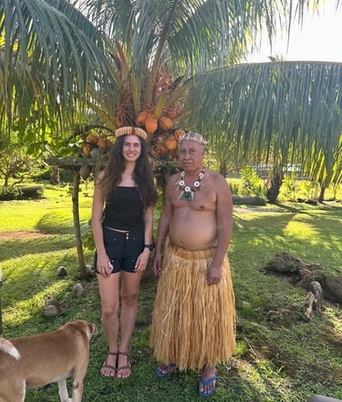 tourist posing with King of Micronesia in traditional grass skirt attire under a coconut palm tree.