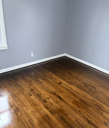 High Shine dark oak hardwood flooring in a room with light grey walls and white baseboards.