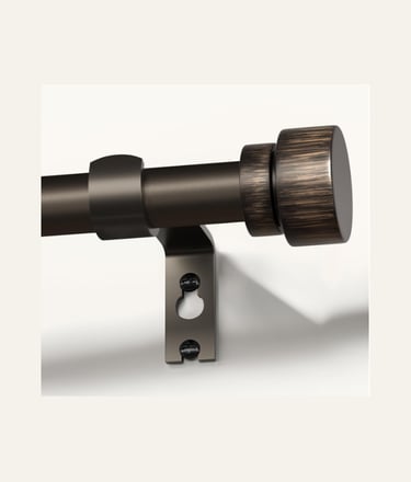 Antique bronze curtain rod with a decorative cylinder finial mounted on a wall bracket.