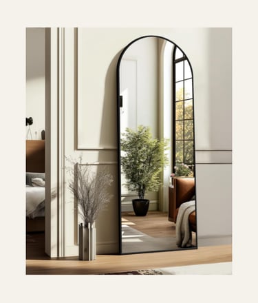 Modern black framed arched full length floor mirror in a bright bedroom interior.