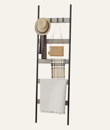Rustic wood and black metal decorative ladder rack holding a hat, purse, scarf, and blanket.