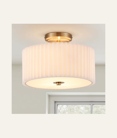 Modern semi-flush mount ceiling light with a pleated white fabric drum shade and antique brass finish.