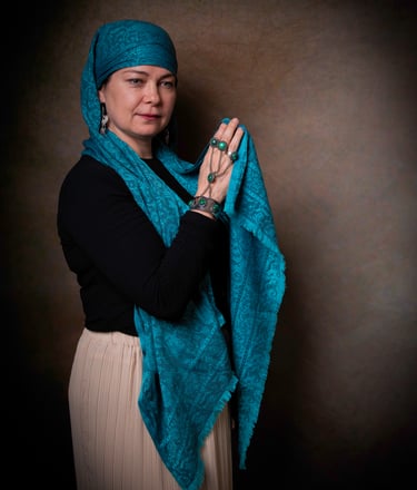 Portrait of a Kazakh woman wearing traditional scarf and jewellery.